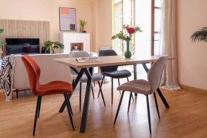 mesa de comedor en salón con sillas de varios colores 