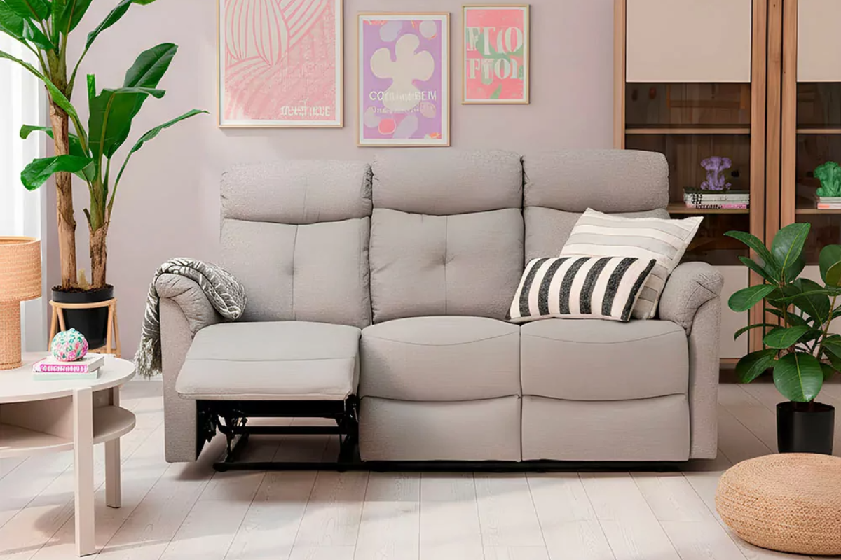 vista de frente de sofá 3 plazas color gris claro con cojines. En un salón decorado con cuadros 