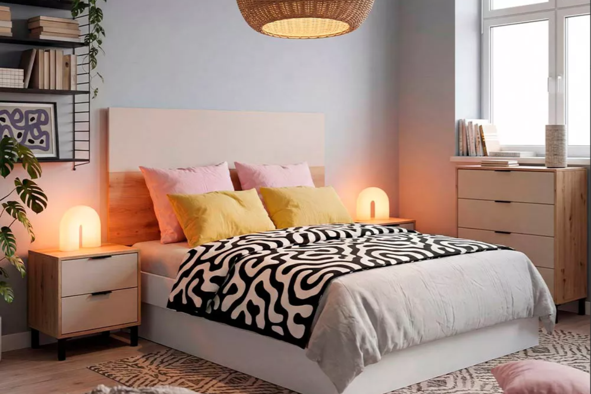 canapé en habitación decorada con mesitas de noche, con colchón de matrimonio y cojines encima 