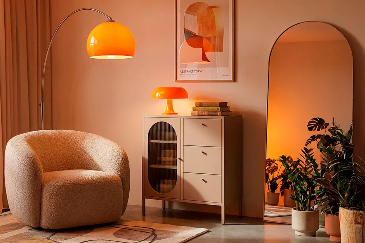 aparador metalico color arena con patas, con lámpara y libros encima de decoración