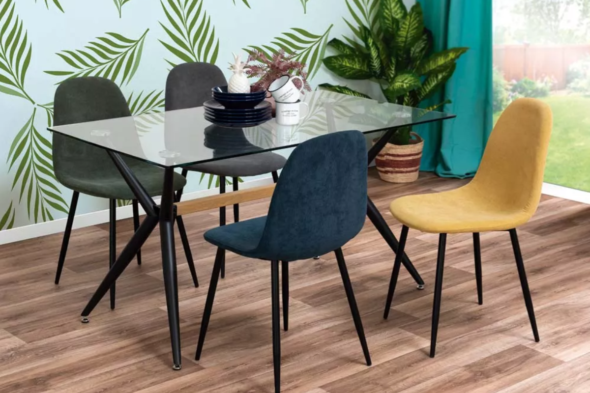 sillas de comedor tapizadas, de color azul, amarillo y gris alrededor de una mesa de cristal